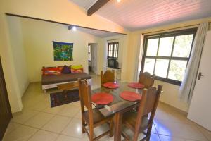 a dining room with a table and a couch at Vila da Sol Itaipava casas e estúdios in Itaipava