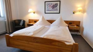 ein Schlafzimmer mit einem großen Bett mit weißen Kissen in der Unterkunft Hotel Burg Breuberg in Höchst im Odenwald