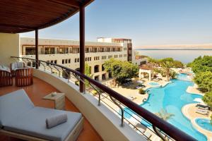 a balcony with a view of a resort with a pool at Dead Sea Marriott Resort & Spa in Sowayma