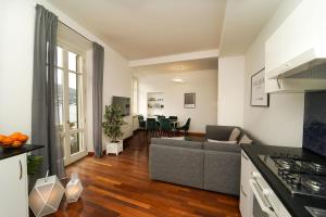 ein Wohnzimmer mit einem grauen Sofa und einer Küche in der Unterkunft Appartamento esclusivo fronte lago, in centro a Como con garage in Como