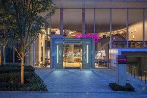 大阪的住宿－大阪本町萬豪慕奇夕酒店，一座带粉红色 ⁇ 虹灯标志的玻璃门的建筑