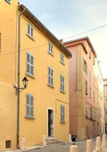 a yellow building with white shutters on a street at Maison Saint-Tropez in Saint-Tropez