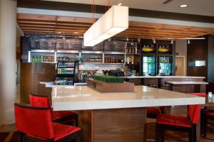 a bar with red chairs and a large counter at Courtyard by Marriott Dallas Midlothian at Midlothian Conference Center in Midlothian