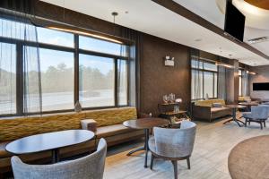 uma sala de espera com mesas, cadeiras e janelas em SpringHill Suites by Marriott Cincinnati Midtown em Cincinnati