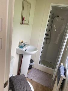 a white bathroom with a sink and a shower at Borwick Lakes Haven in Burton