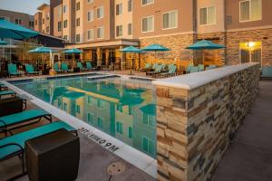 a pool with chairs and umbrellas at a hotel at Residence Inn by Marriott Dallas at The Canyon in Dallas