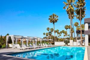 a swimming pool with lounge chairs and palm trees at Westdrift Manhattan Beach, Autograph Collection in Manhattan Beach