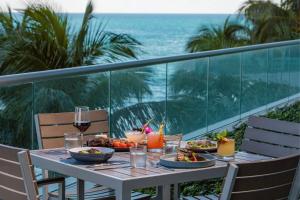 a table with food and drinks on a balcony with the ocean at The Ritz-Carlton Bal Harbour, Miami in Miami Beach