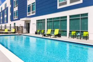 a swimming pool with yellow chairs and a building at SpringHill Suites by Marriott Tallahassee North in Tallahassee