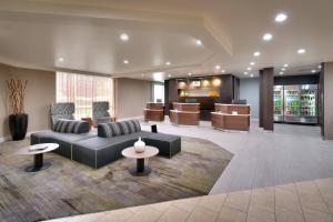 eine Lobby mit einem Sofa, Stühlen und einem Tisch in der Unterkunft Courtyard by Marriott Charlotte Airport/Billy Graham Parkway in Charlotte