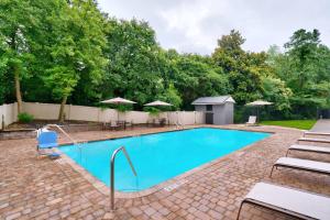 una piscina con sillas y sombrillas en Courtyard by Marriott Charlotte Airport/Billy Graham Parkway, en Charlotte