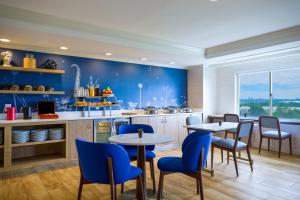 una cocina con paredes azules, mesas y sillas en Renaissance Meadowlands Hotel, en Rutherford