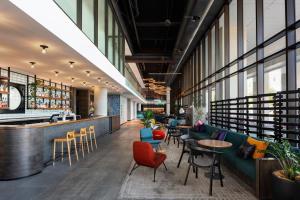 a lobby with tables and chairs and a bar at Aloft Perth in Perth