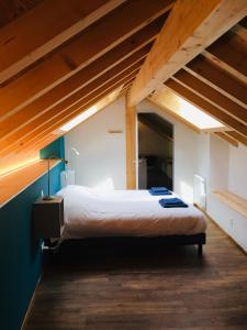 Cama grande en habitación con techo de madera en Hôtel Le Cassini, en Le Freney-dʼOisans