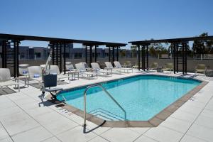 a swimming pool on a roof with chairs and tables at Element Irvine in Irvine