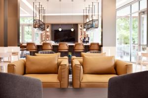 a lobby with brown leather chairs and a bar at AC Hotel by Marriott Atlanta Perimeter in Atlanta