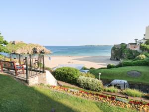 a view of a beach with a bench and the ocean at Sandtop in Tenby