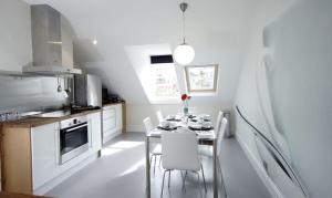 a kitchen with a table with white chairs in it at Bath View Apartments in Bath