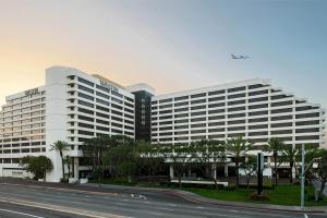 an airplane is flying over a large building at The Westin Los Angeles Airport in Los Angeles