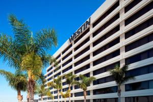 a tall white building with palm trees in front of it at The Westin Los Angeles Airport in Los Angeles