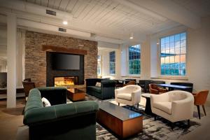 a living room with couches and chairs and a fireplace at Fairfield Inn & Suites Madison Historic Eagle Cotton Mill in Madison