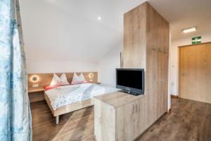 sypialnia z łóżkiem i telewizorem z płaskim ekranem w obiekcie Kammerhof Apartment Traube w mieście Lana