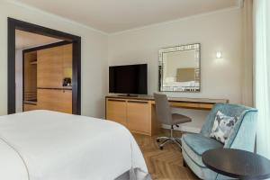 a bedroom with a bed and a desk and a television at The Westin Grand Berlin in Berlin