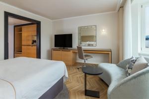 a hotel room with a bed and a couch and a tv at The Westin Grand Berlin in Berlin