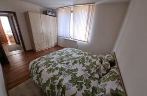 a bedroom with a bed with a green comforter at Банско Апартментс in Bansko