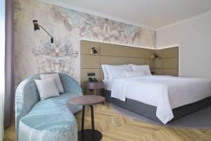 ein Hotelzimmer mit einem großen Bett und einem Stuhl in der Unterkunft The Westin Grand Berlin in Berlin