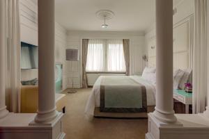 a white bedroom with a bed and a desk at The Westin Grand Berlin in Berlin