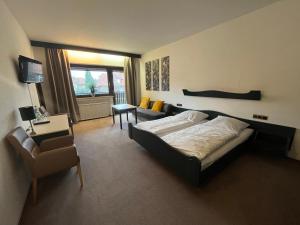 a bedroom with a bed and a chair and a table at Hotel Wolfsjäger in Herbern