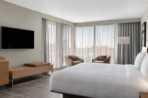 um quarto de hotel com uma cama branca e uma televisão em AC Hotel by Marriott Cape Town Waterfront em Cidade do Cabo