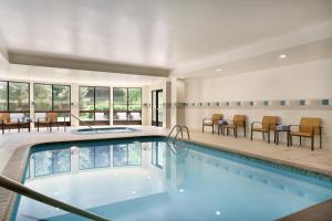 a pool in a hotel room with chairs and tables at Courtyard Ewing Hopewell in Ewing