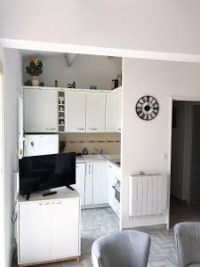 a kitchen with white cabinets and a flat screen tv at Neptuna- 52B- Appart spacieux- 7 pers in Cap d'Agde