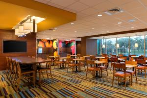 a dining room with tables and chairs and a flat screen tv at Fairfield Inn & Suites by Marriott Orlando East/UCF Area in Orlando