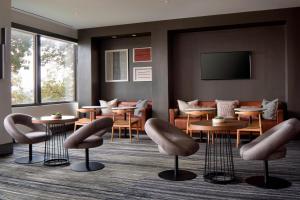 a waiting room with tables and chairs and a flat screen tv at New York LaGuardia Airport Marriott in Queens