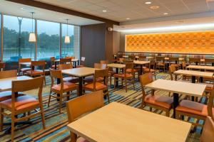 un comedor con mesas, sillas y ventanas en Fairfield Inn & Suites by Marriott Orlando East/UCF Area, en Orlando