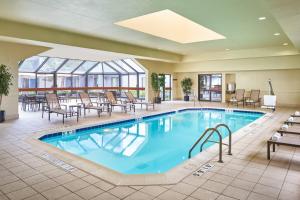 - une piscine dans le hall de l'hôtel avec des chaises et des tables dans l'établissement Courtyard Chicago Wood Dale / Itasca, à Wood Dale