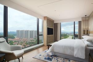 una camera da letto con un grande letto bianco e ampie finestre di Sheraton Yunfu Xinxing Hotel a Yunfu