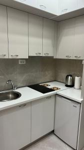 a kitchen with white cabinets and a sink at Apartment Downtown in Podgorica