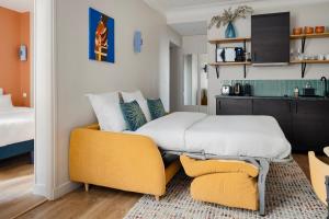 1 dormitorio con cama y sofá amarillo en Edgar Suites Grands Boulevards - Boulanger, en París