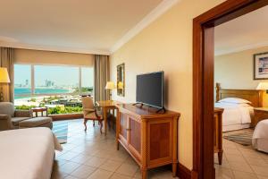 a hotel room with a television and a bedroom at Sheraton Jumeirah Beach Resort in Dubai