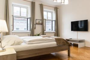 a bedroom with a bed with a tv and windows at comfortable 2BR Apt.-Near Wiener Stadthalle in Vienna