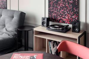a living room with a chair and a table with speakers at STAGES HOTEL Prague, a Tribute Portfolio Hotel in Prague