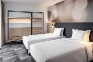 a hotel room with two beds and a mirror at STAGES HOTEL Prague, a Tribute Portfolio Hotel in Prague