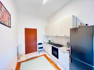 eine Küche mit einem Kühlschrank und weißen Schränken in der Unterkunft Be Your Home - Casa Vacanze Il Posticino in Civitavecchia
