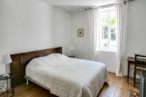 a white bedroom with a bed and a window at Au Coeur du Vignoble in Cadaujac