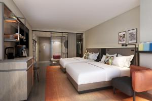 a bedroom with a large white bed and a kitchen at Renaissance New York Flushing Hotel at Tangram in Queens
