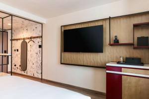 a hotel room with a flat screen tv on a wall at Renaissance New York Flushing Hotel at Tangram in Queens